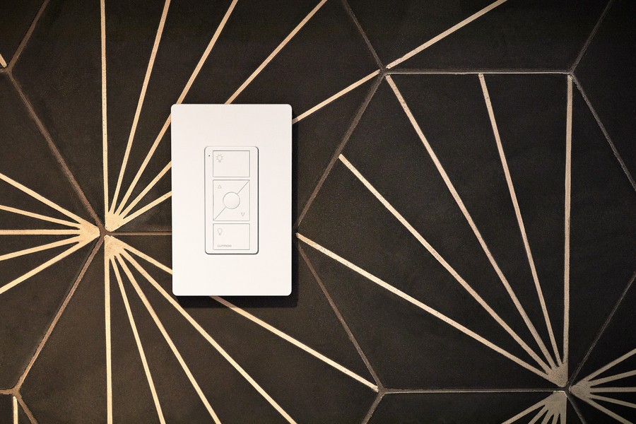 A Lutron smart switch on a black and gold tiled wall.  