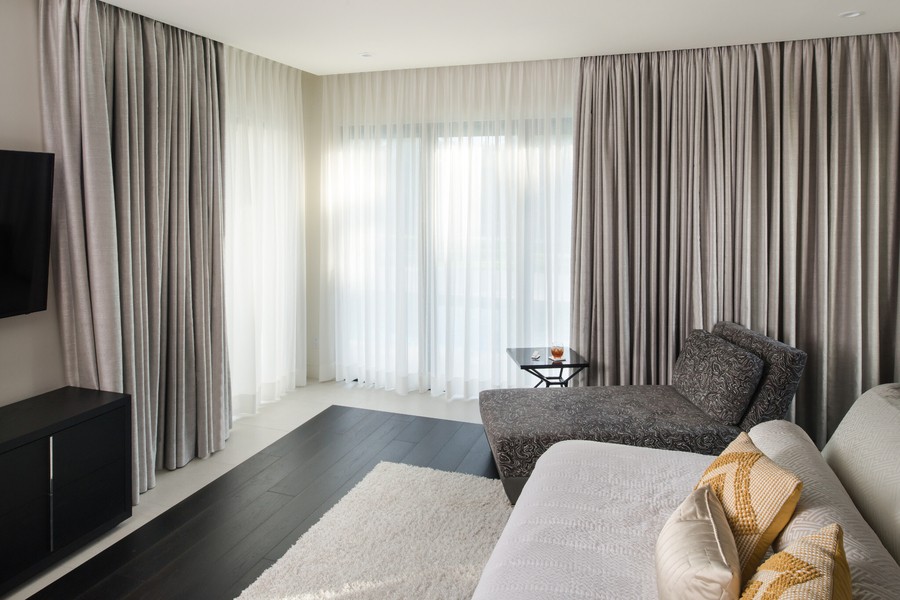  A bedroom with Lutron motorized drapes on the floor-to-ceiling windows. 