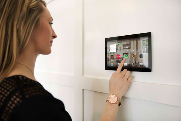 Picture of a homeowner launching Spotify via a touchscreen in their smart home. 