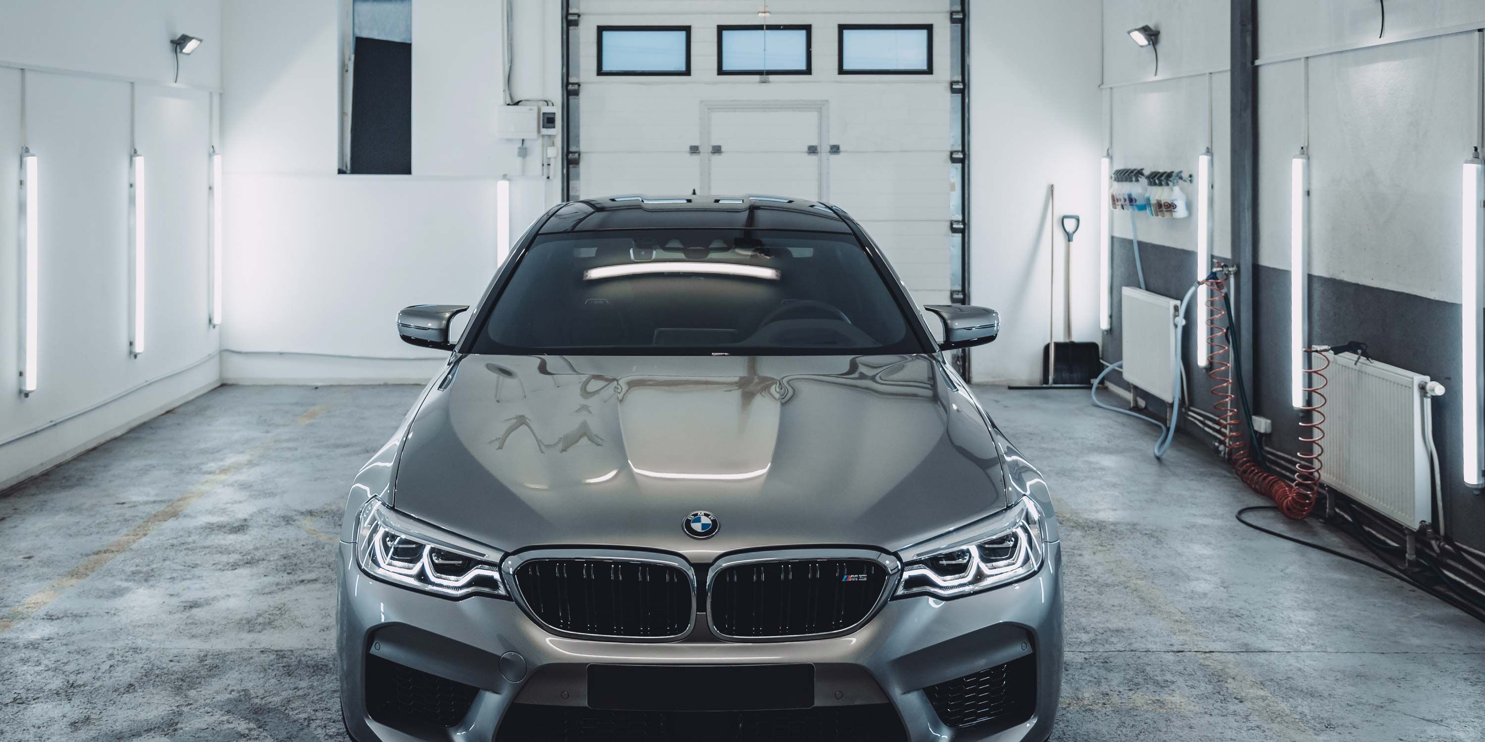 silver bmw in grey and white garage with led lighting on walls