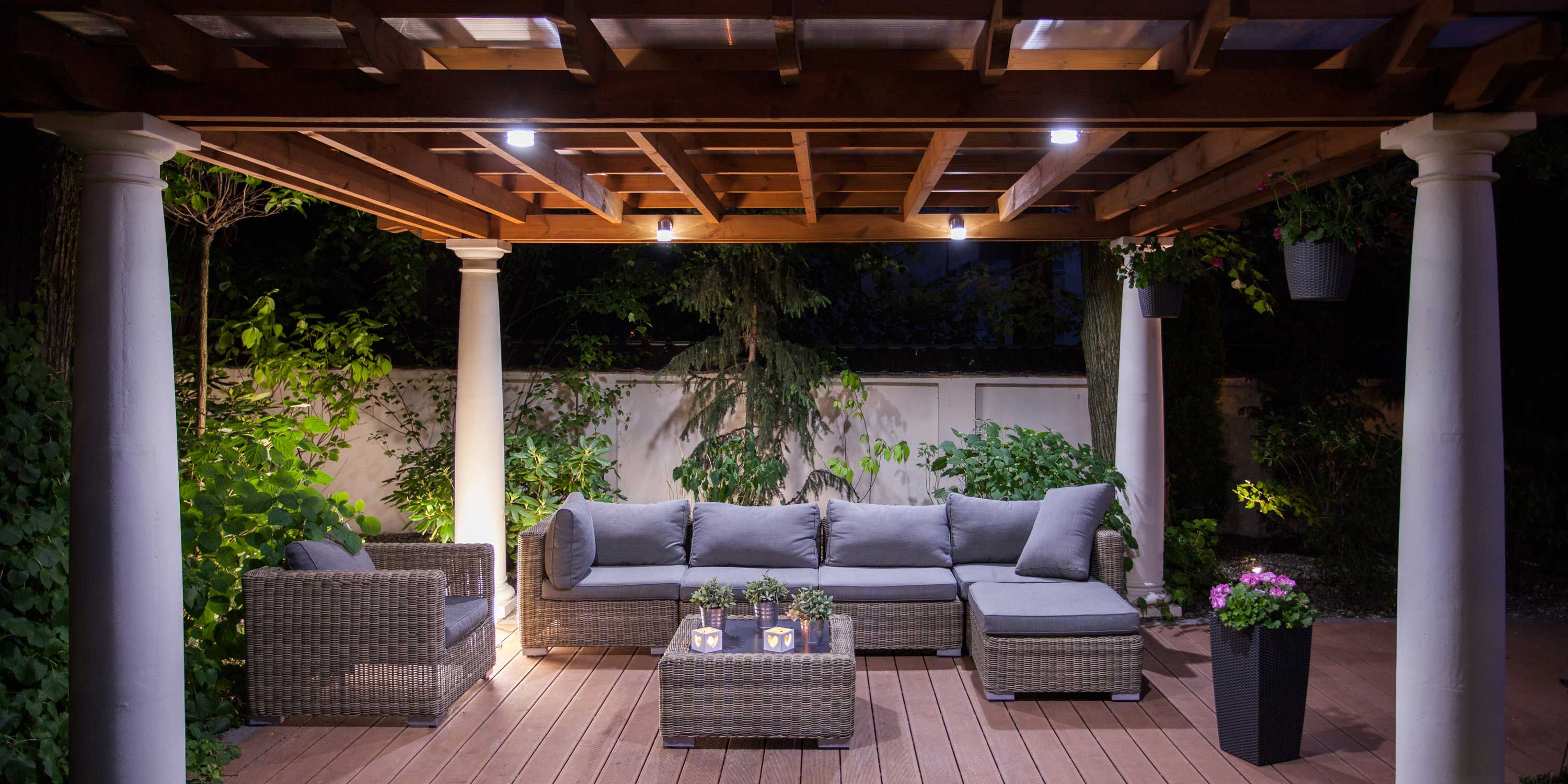 Patio set under wooden gazebo at night with lights on